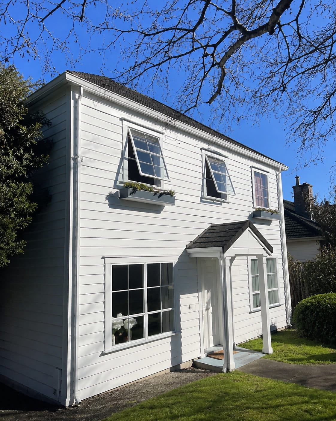 Clean white weatherboard cladding and window joinery on a two-storey Auckland home