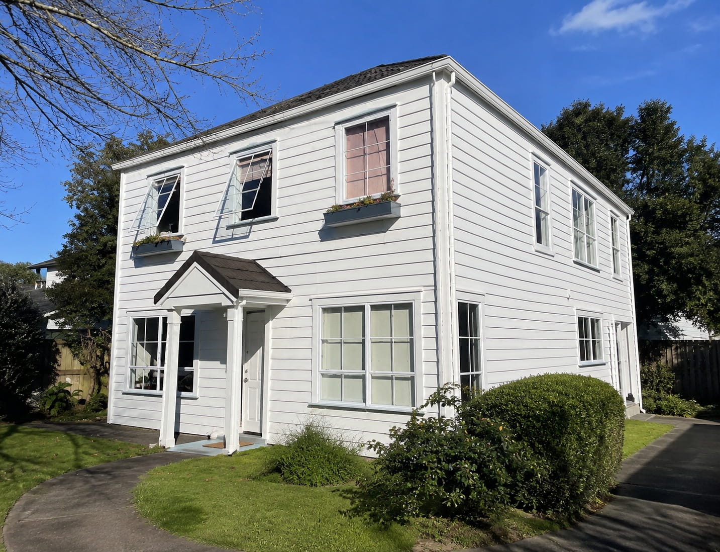 Freshly washed white weatherboard two-storey Auckland home seen from the front path